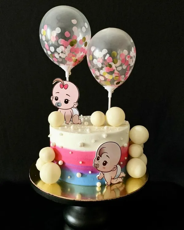 This gender reveal cake with cute baby toppers and confetti balloons is perfect for the big announcement.