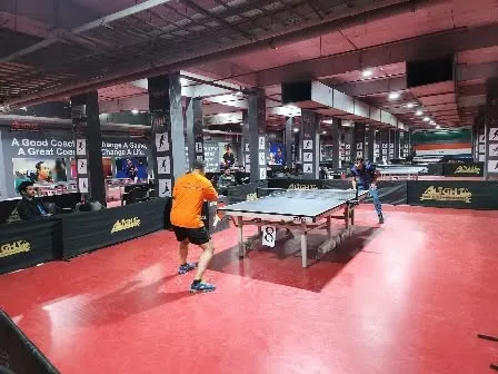 A wide shot of a match in progress during a corporate tournament. You can see the professional setup with multiple tables and ample space for players.
