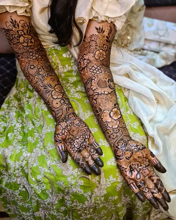 A full-coverage bridal mehndi design extending up to the elbows. This intricate artwork features a dense mix of floral motifs, traditional paisleys, and delicate filler patterns, creating a rich and luxurious look for the bride's big day.