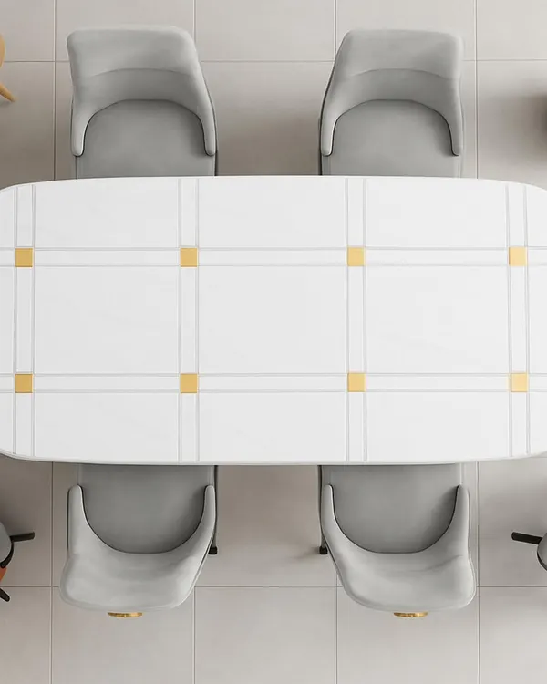 This top-down view shows the clean, geometric pattern of a modern dining table. The white surface is accented with gold-finished squares, creating a look of understated luxury. Paired with soft grey upholstered chairs, this set is perfect for a contemporary dining space.