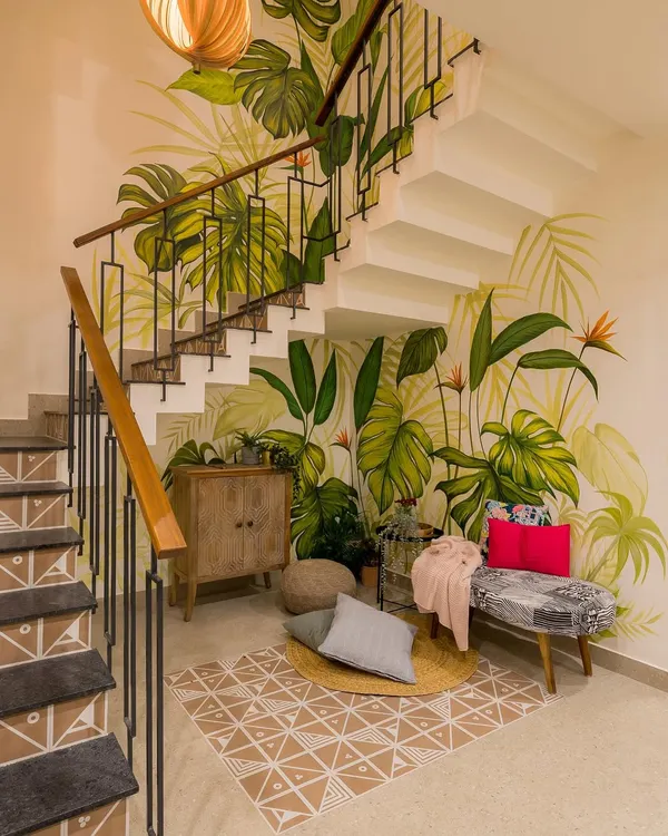A cozy nook created under the staircase, brought to life by a vibrant, hand-painted tropical mural. This space, once overlooked, is now a beautiful and inviting corner for reading or relaxing.