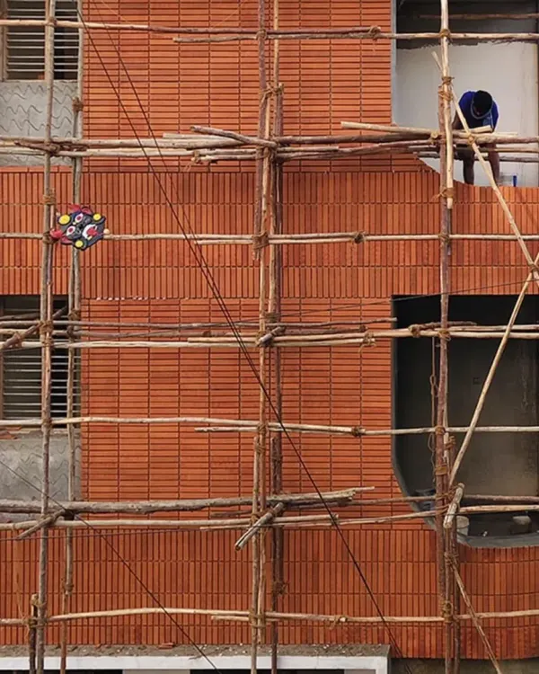 The 'Kutumb' project in progress. You can see the texture and pattern of the brick facade as it's being meticulously applied by artisans. The bamboo scaffolding is a traditional and sustainable method in itself.