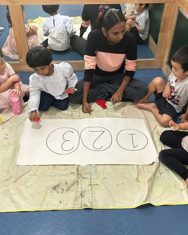 A teacher guides a group of children in a number recognition activity. Using hands-on materials makes learning to count from 1 to 3 a fun game.