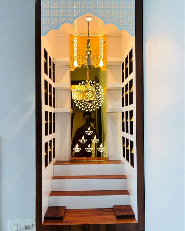 This is the interior of a custom pooja unit I designed. It features a mirrored back with an etched 'Om' and diya motifs, which are beautifully illuminated by internal lights. The stepped platform allows for multiple idols.