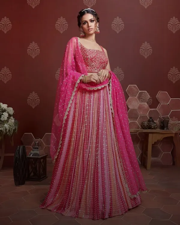 This stunning fuchsia pink lehenga is a masterpiece of intricate embroidery and flowing fabric. It's designed for the woman who wants to make a grand entrance, perfect for a wedding reception or sangeet night.