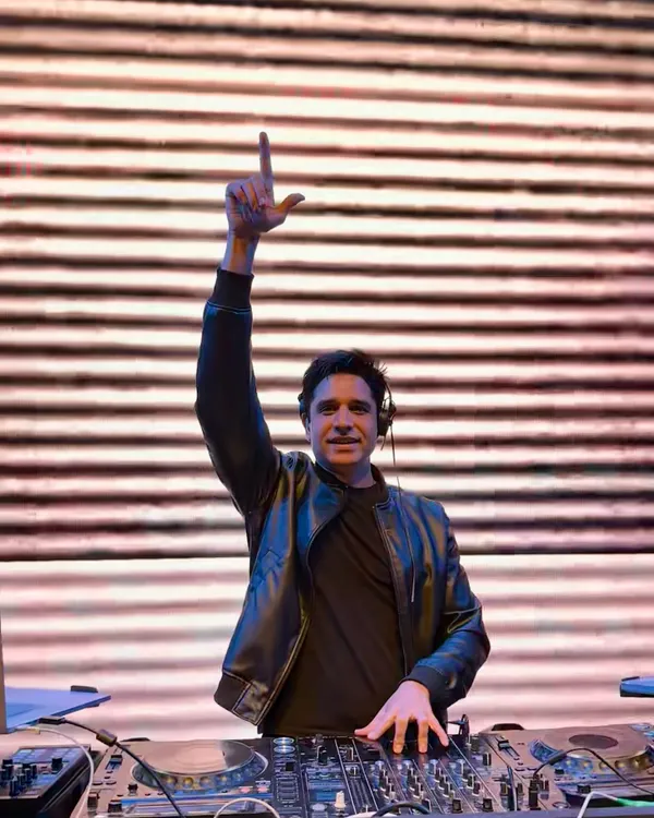 In the zone behind the decks, with my hand up, feeling the energy of the crowd. This is my happy place, where I connect with the music and the people.