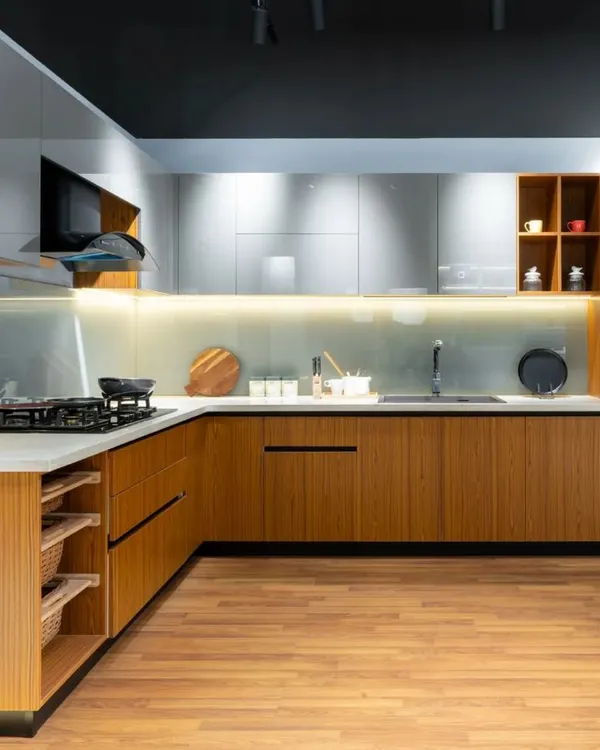 This spacious L-shaped kitchen beautifully marries warm wood base cabinets with sleek, light grey glossy uppers. The design includes open wicker basket drawers and an integrated oven unit, creating a perfect blend of natural textures and modern convenience.