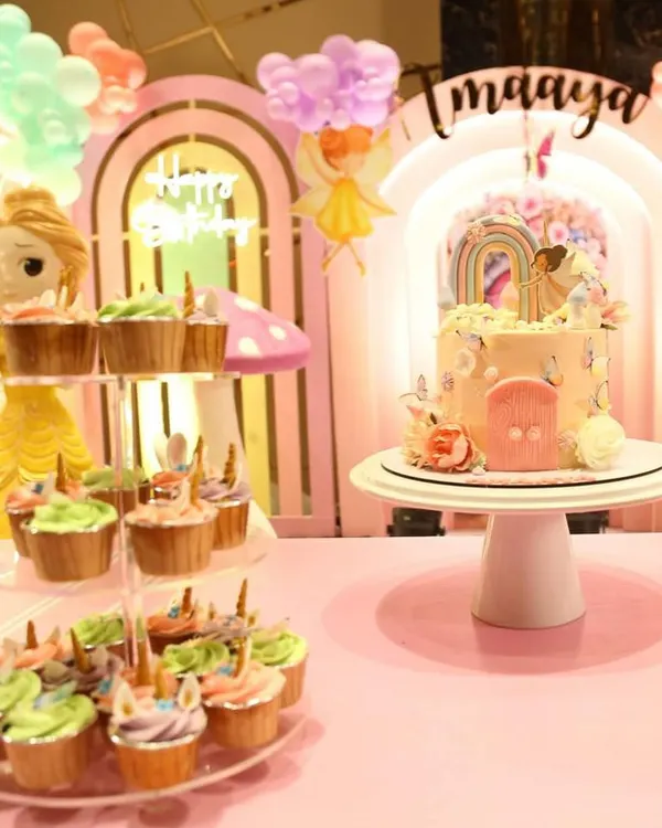 Here is a closer look at the "Wonderland" dessert table we created for Imaaya's birthday. The centerpiece cake, with its delicate fairy and rainbow topper, is perfectly complemented by a tiered stand of matching unicorn cupcakes.