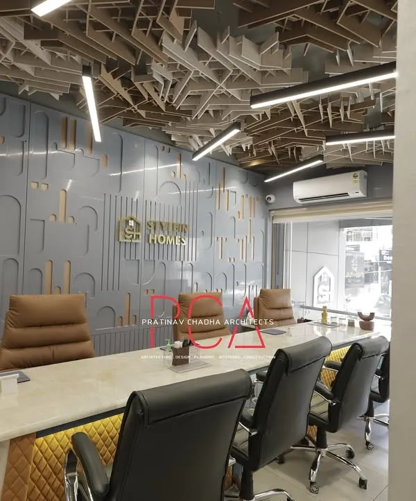 A wider perspective of the StyleIn Homes conference room, showing how the intricate ceiling, paneled wall with brand logo, and luxurious seating come together to create a powerful and professional meeting environment.