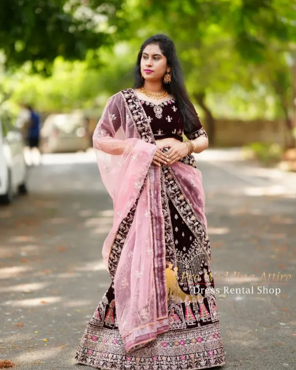This is a full view of my dark velvet lehenga, which features intricate doli and baraat embroidery along the border. It's paired with a contrasting light pink net dupatta for a balanced look.