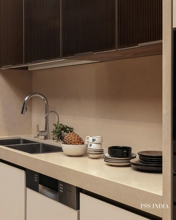 Styling turns the everyday into a curated moment. A touch of greenery, a bowl of fresh fruit, and perfectly stacked ceramics on the countertop add life and personality to this modern kitchen.