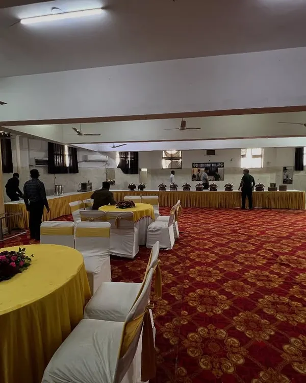 A full view of a banquet hall setup, showing our round table seating arrangement and a long buffet line in the background. We handle setups for large gatherings.