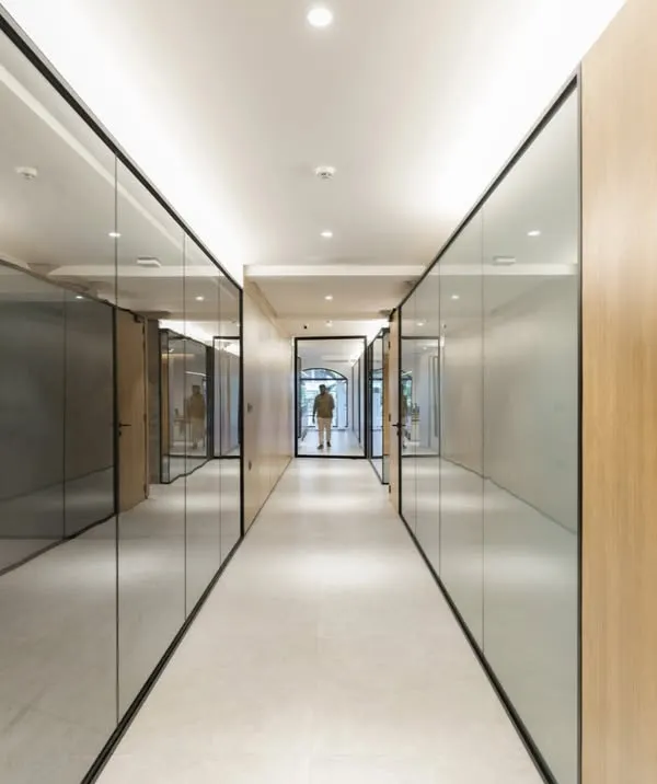 For a high-intensity infrastructure company, we designed a workspace that brings a sense of calm and order. The corridor uses reflective glass and clean wood paneling to create a streamlined path, reinforcing a feeling of clarity and purpose amidst a complex business environment.