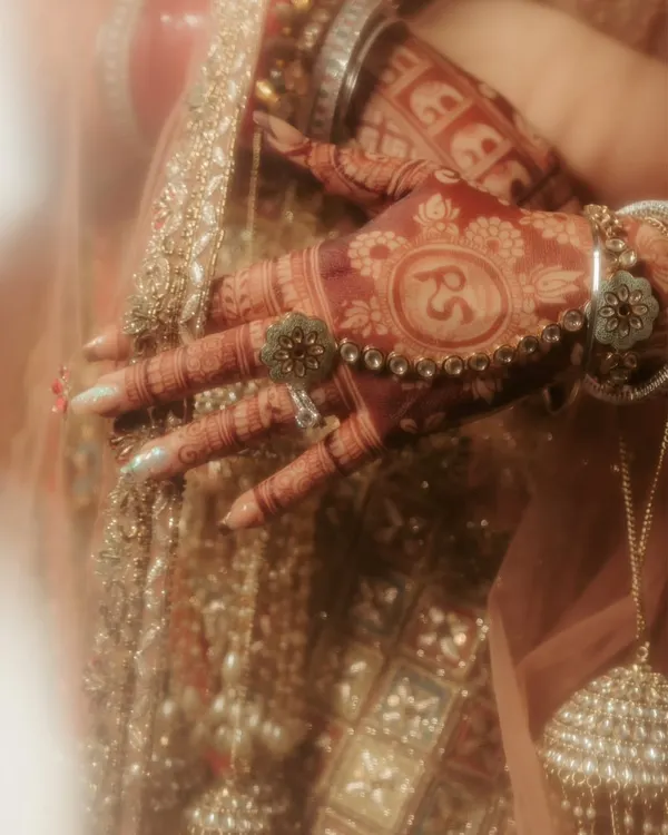 A close-up on the bride's hands, showcasing the beautiful, deep color of her henna and the custom initials 'RS' for Raghavi and Shivam, a personal touch I love to capture.