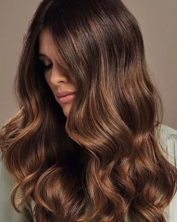 This is a perfect example of a rich, multi-tonal brunette. The soft waves showcase the seamless blend of deeper roots and lighter, warmer ends, creating a look of effortless elegance and healthy shine.