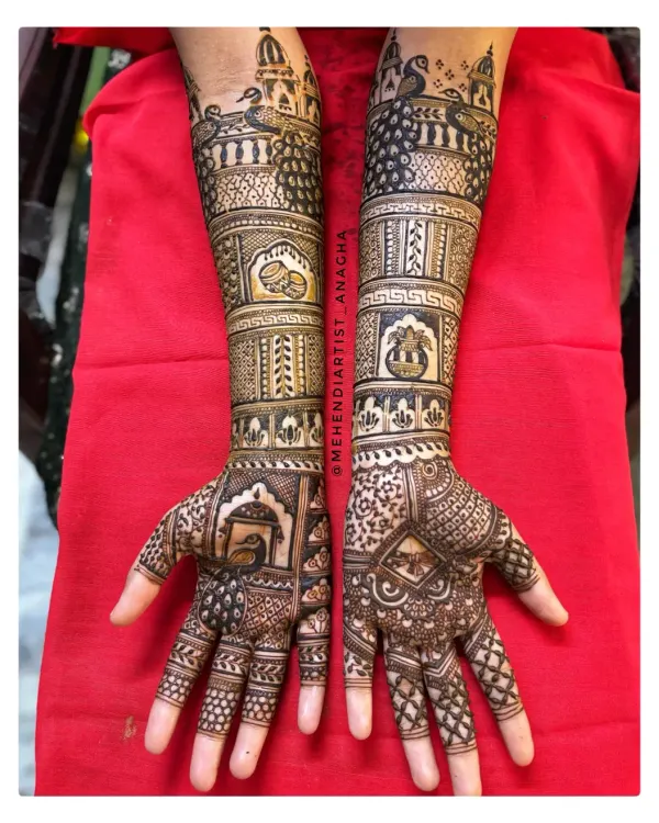 A complete bridal mehendi design extending up the forearms. This piece incorporates traditional Rajasthani elements like peacocks and architectural details, demonstrating a high level of skill in composition and detail.