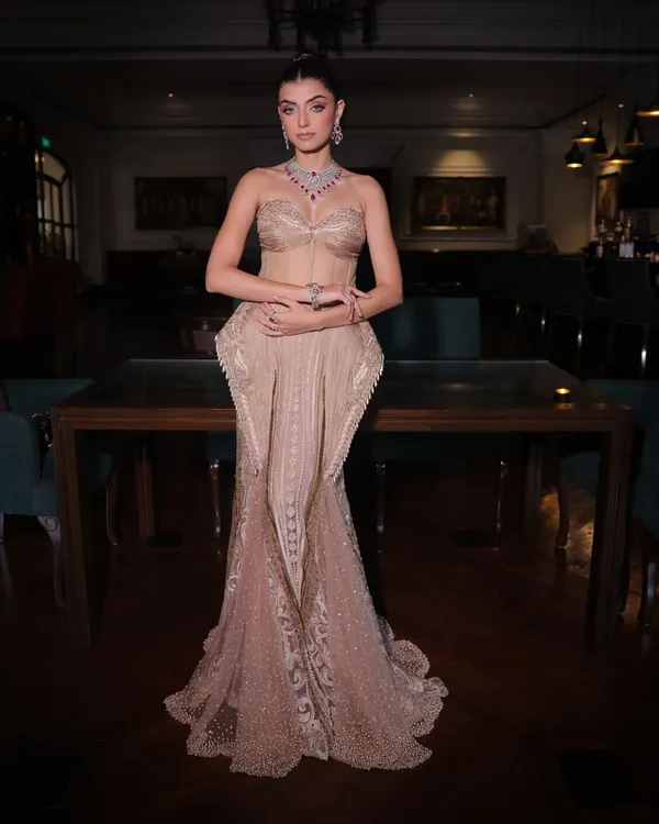 A full-length view of a bespoke champagne silk gown. The design features a structured corset bodice and a fish-cut skirt with intricate handwork, creating a silhouette that is both timeless and personal.