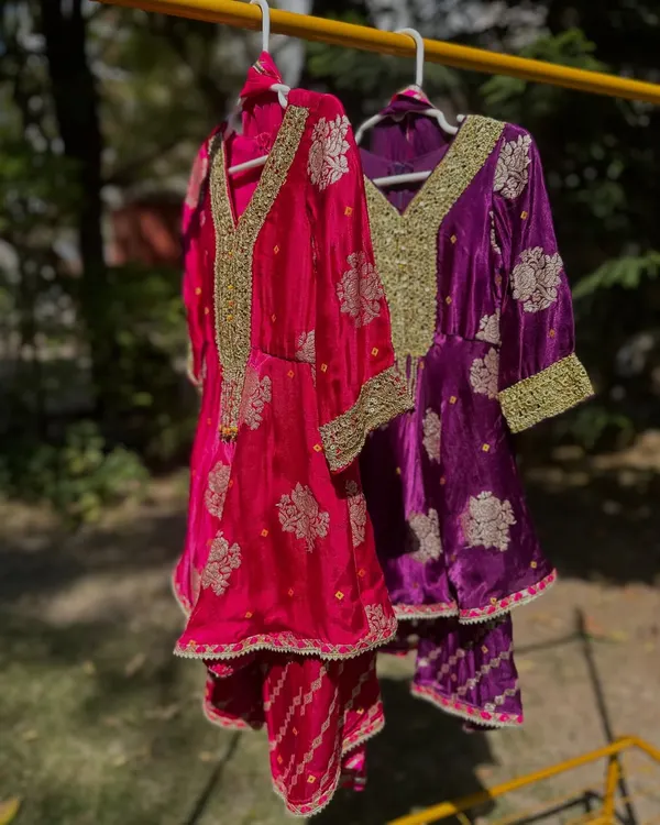 Here are two of my most popular Gota Patti sharara sets, hanging side-by-side. You can see the rich velvet fabric and the intricate gold embroidery that makes these outfits so luxurious and perfect for weddings.