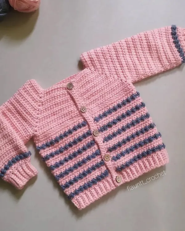 This is the Dewdrops Cardigan, a cozy and stylish piece for winter. The design features textured bobble stitch stripes and simple wooden buttons, making it a timeless handmade sweater.