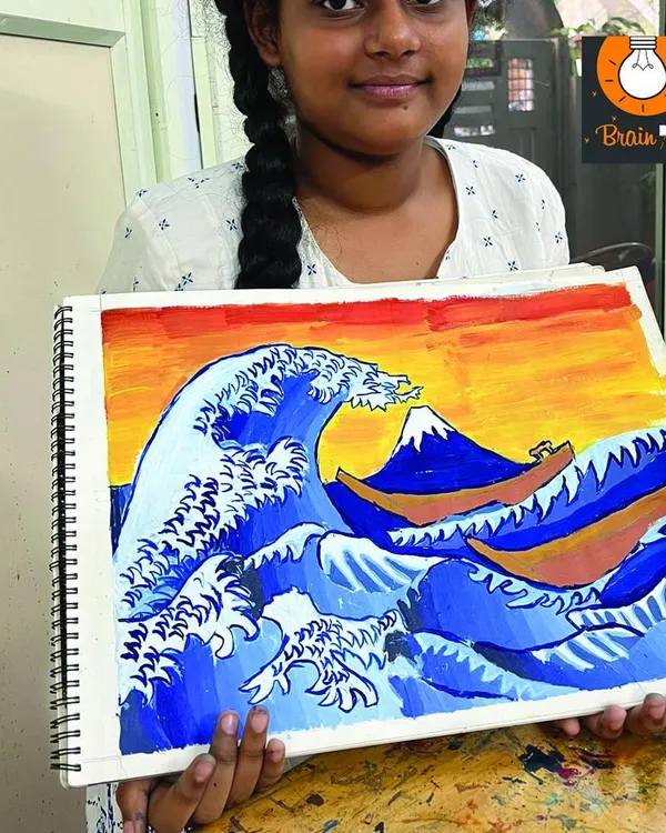 A student proudly holds up her painting of 'The Great Wave off Kanagawa'. We introduce young artists to famous artworks to inspire their own creations.