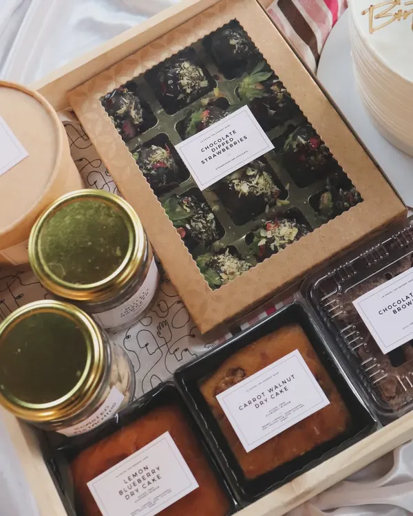A look inside one of my custom wooden tray hampers. This one includes dry cakes, brownies, chocolate-dipped strawberries, and jars of snacks.