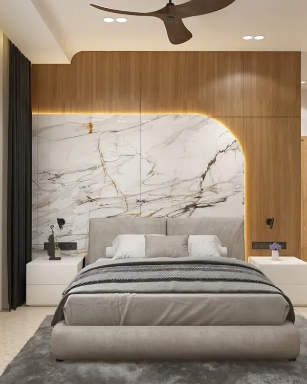 This hotel bedroom in Shimoga features a stunning headboard that combines the warmth of wood paneling with the elegance of book-matched marble. Backlighting accentuates the curved design, creating a sophisticated and inviting focal point.