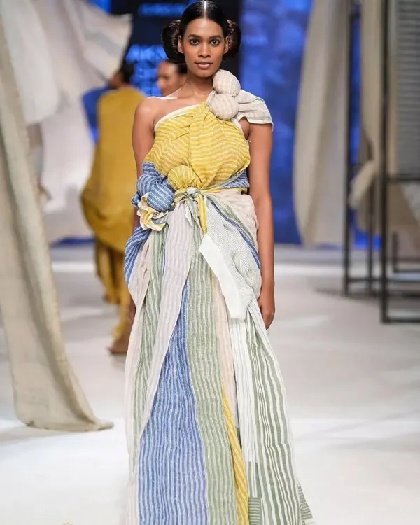 A stunning runway look for designer Anavila Misra at Lakmé Fashion Week. The makeup is clean and earthy, paired with a structured bun to complement the handwoven, sustainable fabric and intricate draping of the garment.