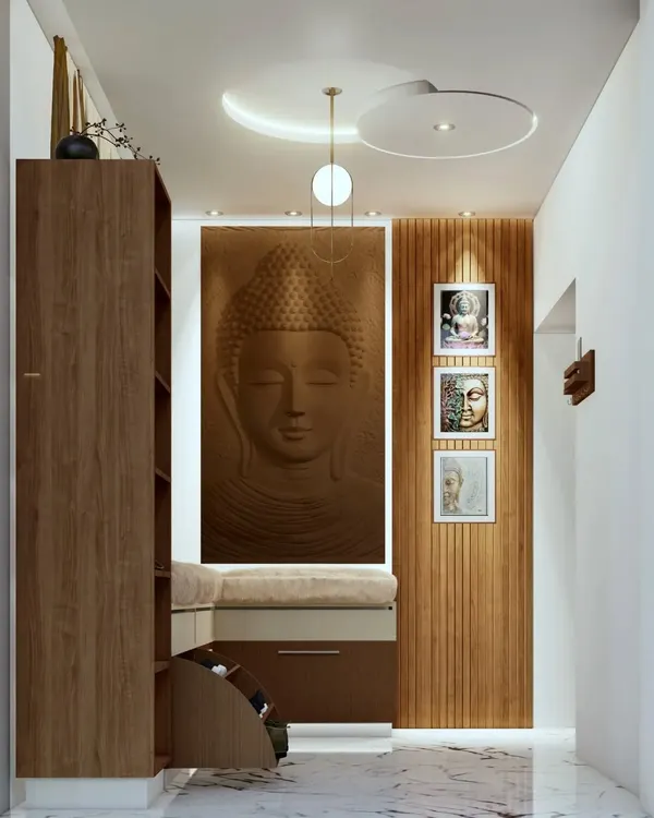 A foyer design for a home in Mysore's Police Layout, featuring a serene Buddha relief panel, a cushioned seating bench with built-in shoe storage, and elegant false ceiling lights.