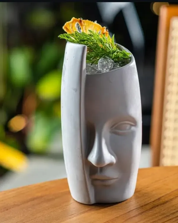 This cocktail is served in a custom ceramic glass shaped like a face, turning the drink itself into a piece of art. Sourcing unique glassware is a key part of my bar consulting service.