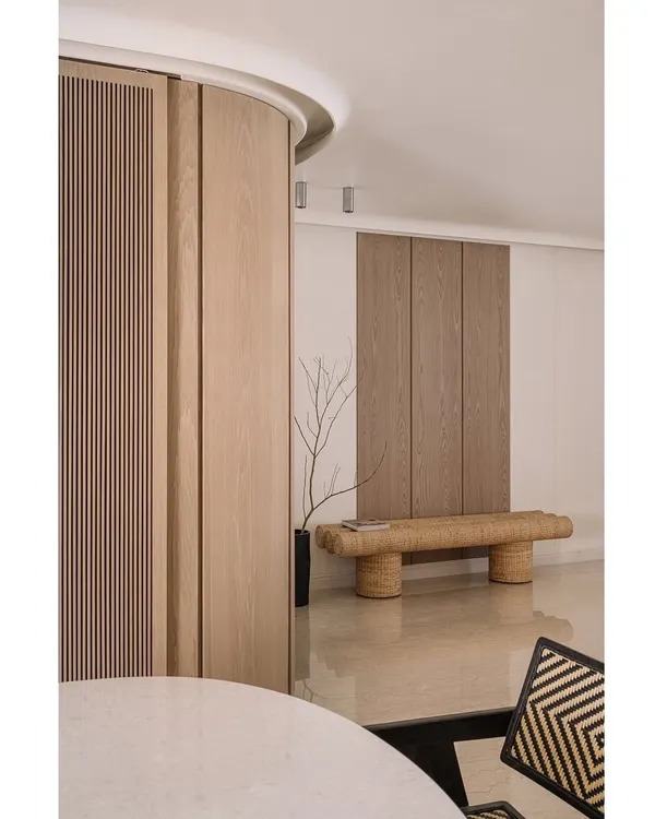 Welcome to Kanso House. The entrance features a curved wooden wall and a woven bench, immediately setting a tone of natural simplicity and calm.