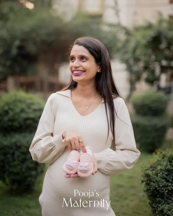 A beautiful outdoor maternity portrait taken in a garden setting. The soft, natural light is perfect for creating a warm and gentle look, and the baby shoes add a sweet touch.