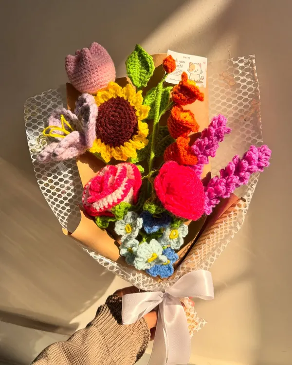 A stunning and colorful mixed bouquet, featuring a sunflower, rose, tulip, and other beautiful blooms, captured in the warm glow of the sun.