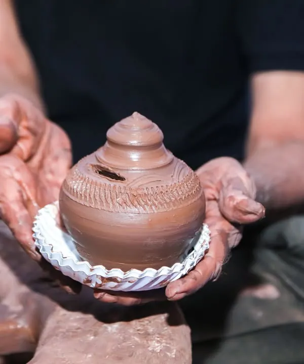 A master potter demonstrating how to shape clay on a wheel at our pottery station. Guests get to try their hand at creating their own small pot.