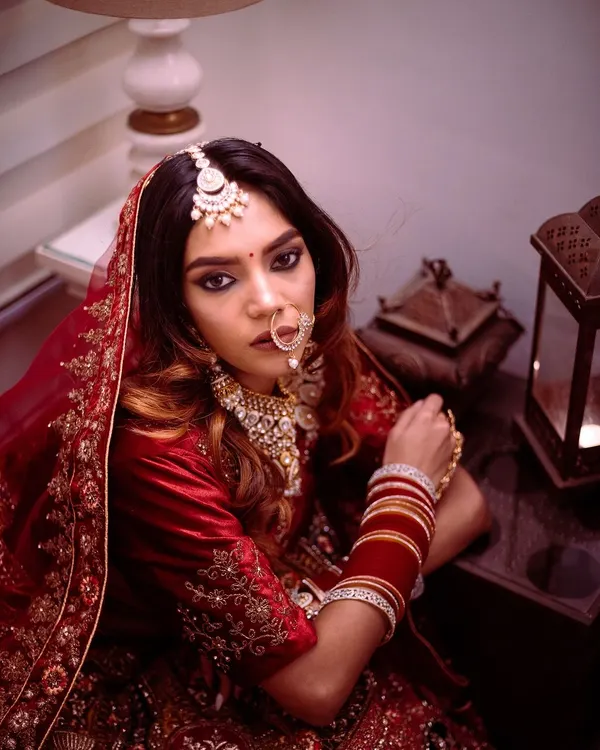 For me, a bridal portrait is about capturing a feeling. Here, I used moody, dramatic lighting to highlight the bride's intense gaze and the rich velvet of her traditional red lehenga, creating a look that is both fierce and timeless.