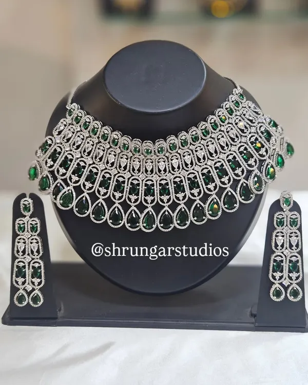 This stunning silver-finish American Diamond necklace with emerald green stones makes a bold statement. It's perfect for a reception or cocktail party.