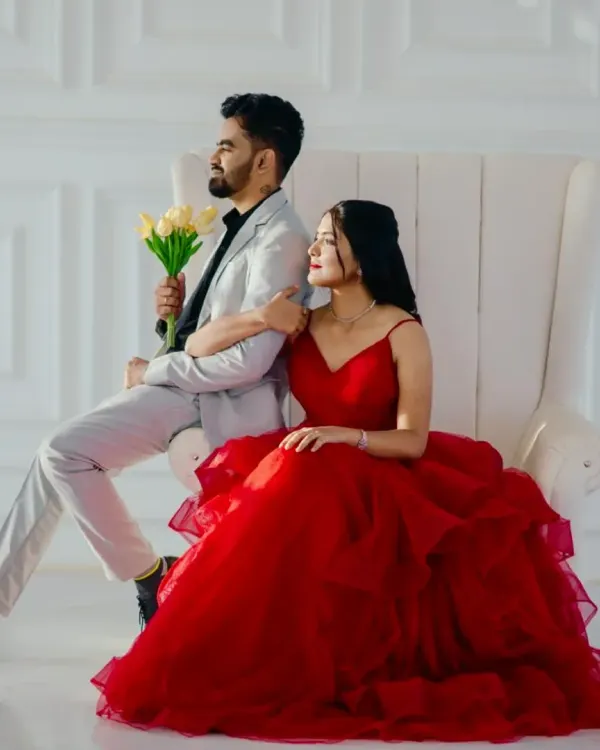 A picture-perfect moment. She is radiant in a classic red tiered ballgown, while he looks sharp in a light grey suit. This is the timeless, romantic look so many couples dream of.
