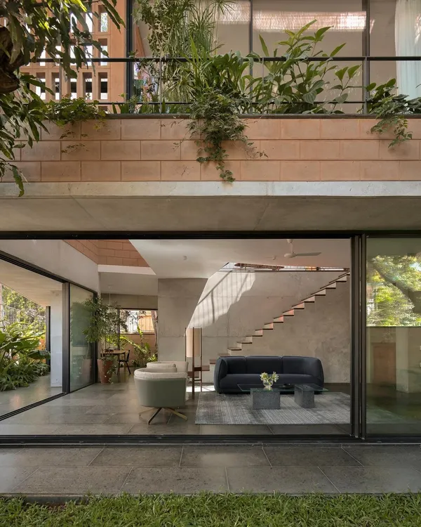 (Hero Media) This is our Debris Block House in Bangalore, where the ground floor opens completely to the landscape. We designed this to maximize the connection to the garden, with light streaming in from skylights and the multi-level open staircase, creating a seamless indoor-outdoor living experience.