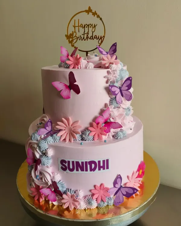 A gorgeous two-tier cake in shades of pink and purple, adorned with a cascade of butterflies and flowers.