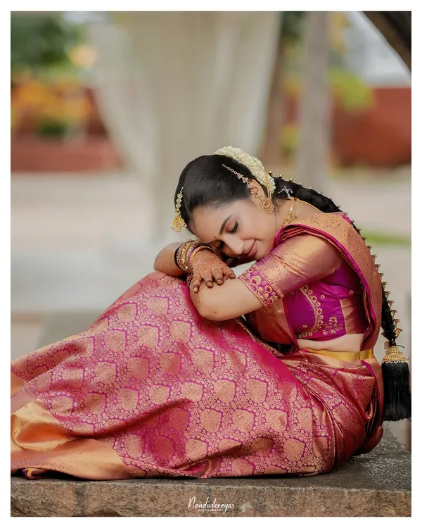 A moment of quiet contemplation for the bride. This artistic portrait in her beautiful pink Kanjeevaram saree captures a sense of peace and grace before the ceremony.
