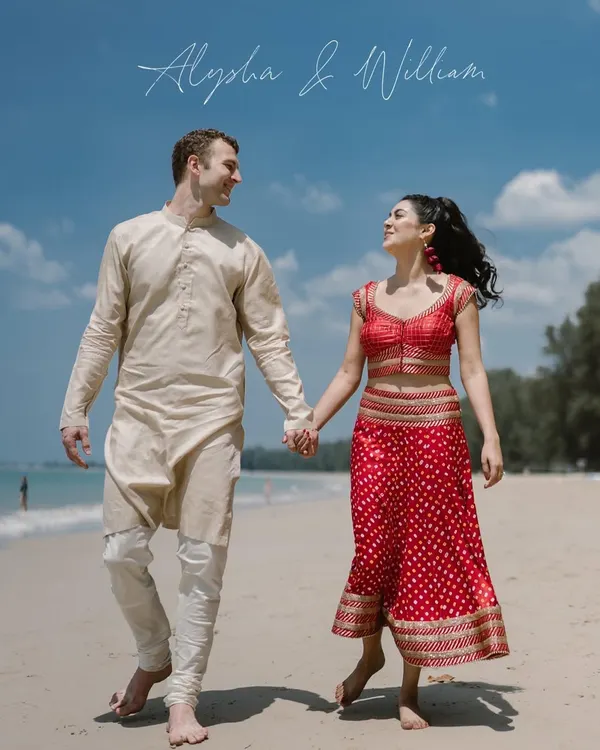 Hand in hand, walking towards forever on a Thai beach. This shot captures the simple romance of a destination wedding, where the couple's traditional Indian attire contrasts beautifully with the sand and sea.