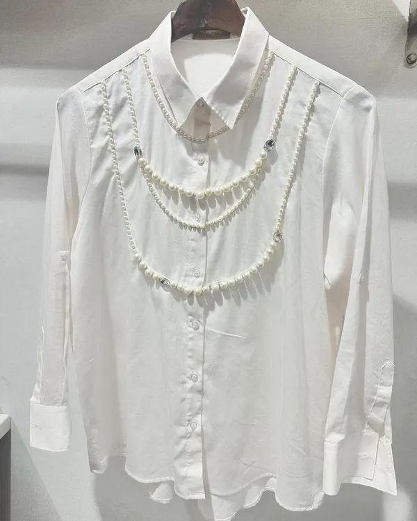 A standout piece from my collection, this opulent Swiss cotton shirt is adorned with hand-draped pearl chains. It’s a perfect example of how I transform a classic shirt into a piece of wearable art.