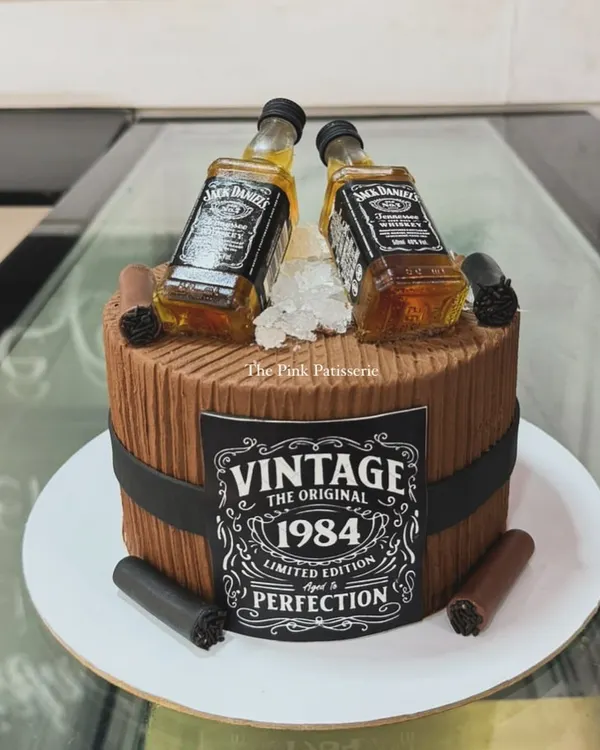 A cake for a vintage enthusiast, designed as a wooden barrel with a custom "Vintage 1984" label and two miniature Jack Daniel's bottles.