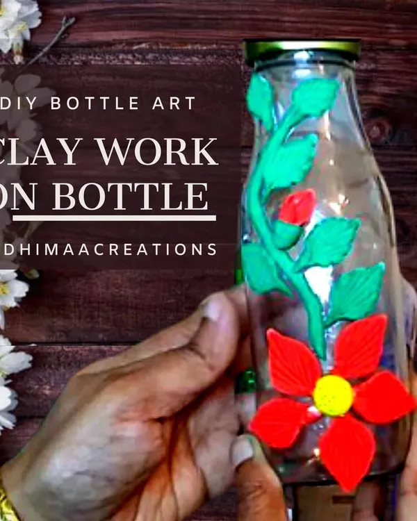 Don't throw away old glass bottles. This image shows how you can upcycle a simple bottle by decorating it with floral designs using air-dry clay, turning it into a beautiful decor piece.