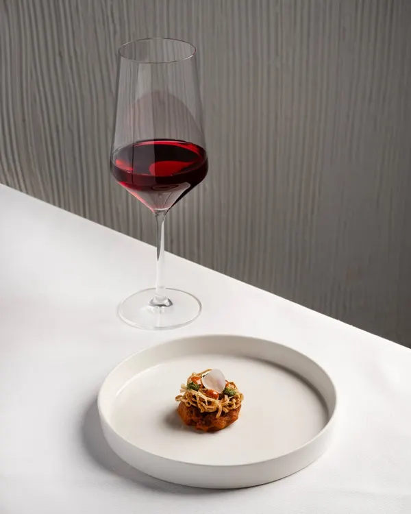 We believe in the perfect partnership between plate and glass. Here, a rich lamb shikampuri filled with boursin and wrapped in crisp urad dal kataifi is paired with a Mourvèdre-Viognier from South Africa. The wine's supple fruit notes beautifully complement the spice and texture of the dish.