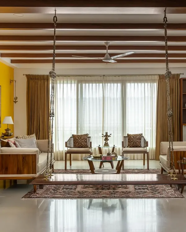 The 'Vasudhalayah' living room is a tribute to Indian heritage. We used antique Chettinad pillars, a traditional swing, and a bold yellow accent wall to create a space that is earthy, vibrant, and full of character.