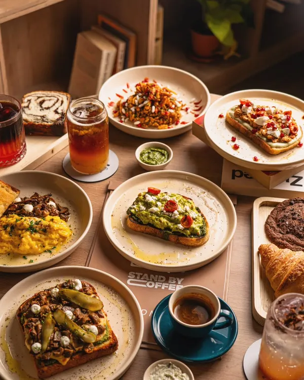 A beautiful spread of brunch dishes from a specialty coffee shop, including avocado toast, scrambled eggs, and pastries. This shot showcases menu variety in a single image.