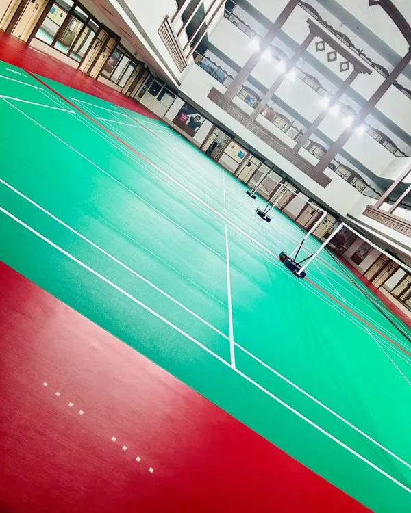 A dynamic, wide-angle view of our courts, showcasing the clean, expansive playing area. The red and green synthetic surface is designed for optimal grip and performance.