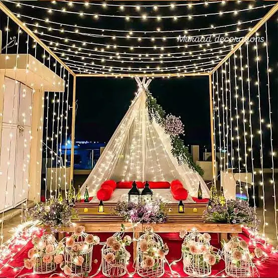 This is one of my most requested romantic setups, perfect for a proposal or anniversary. I create a canopy of fairy lights over a cozy tent with low seating, a red carpet, and decorative birdcages filled with flowers for a truly magical atmosphere.