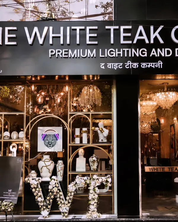 The storefront of The White Teak Company, where we designed the launch event decor. The entrance features custom floral lettering and a glimpse of the quirky, high-end lighting and decor inside, setting the stage for the brand experience.