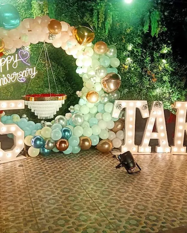 For this grand 25th anniversary, I combined a lush green wall with a pastel balloon arch and large marquee letters spelling out the couple's name. The "Happy Anniversary" neon sign adds a warm, celebratory glow to the venue.
